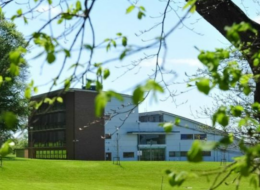 Photo looking between the leaves of a tree across lawn, to ArcLabs Research Centre