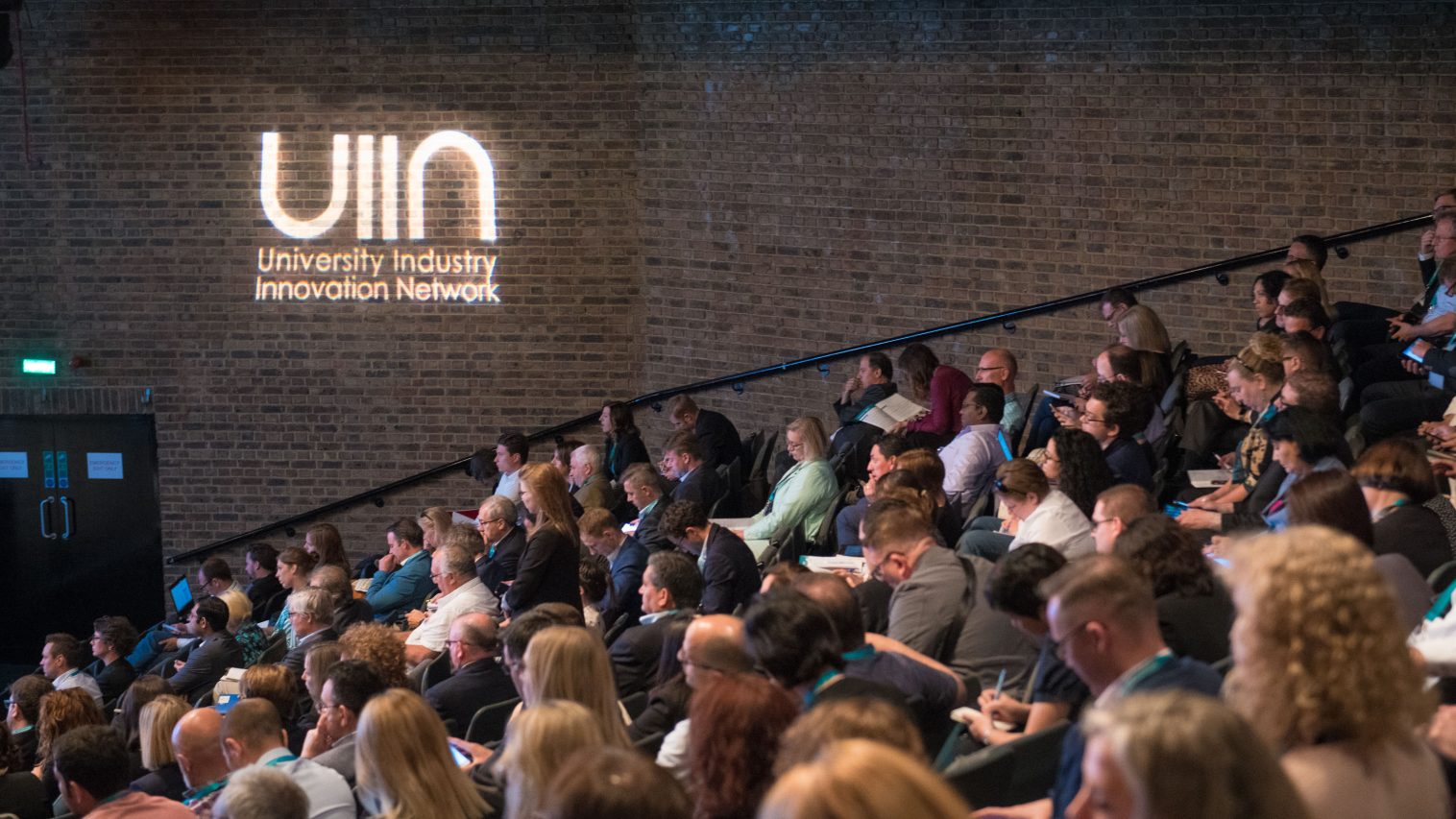 Crowded auditorium at UIIN conference with UIIN logo projected onto wall